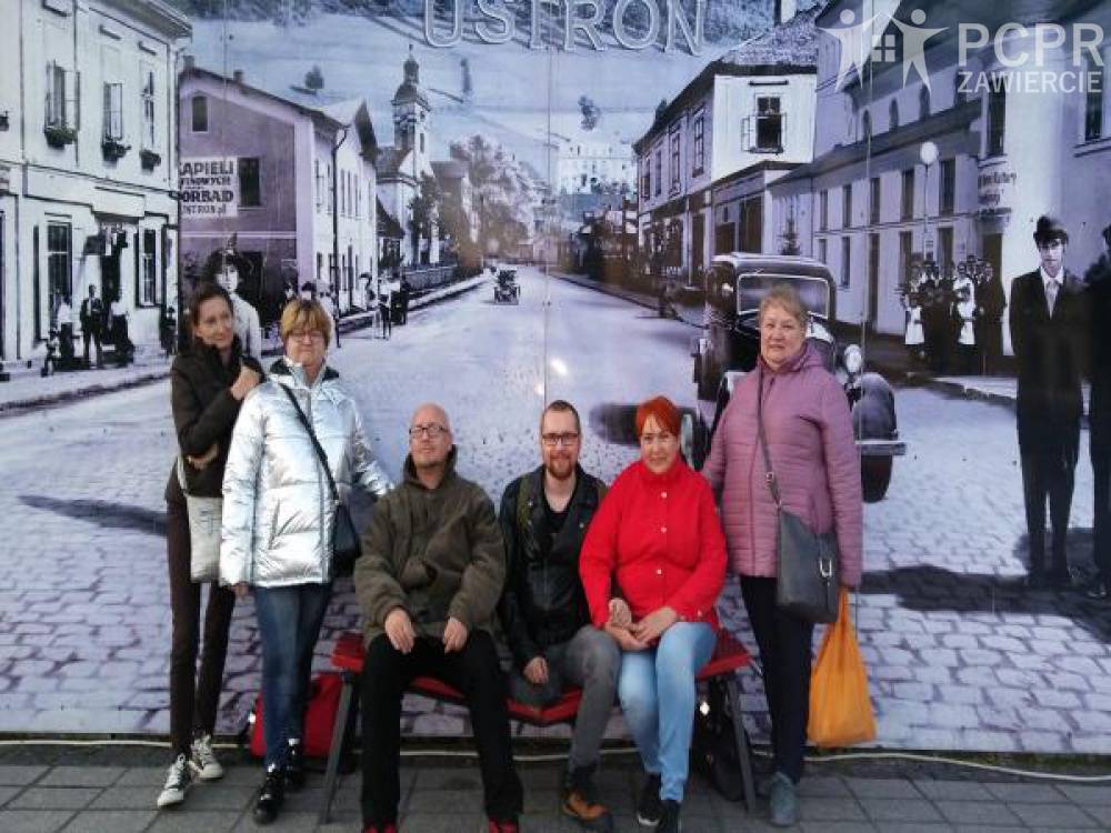 Zdjęcie: Grupa kobiet i mężczyzn na tle fototapety ukazującej miasto Ustroń